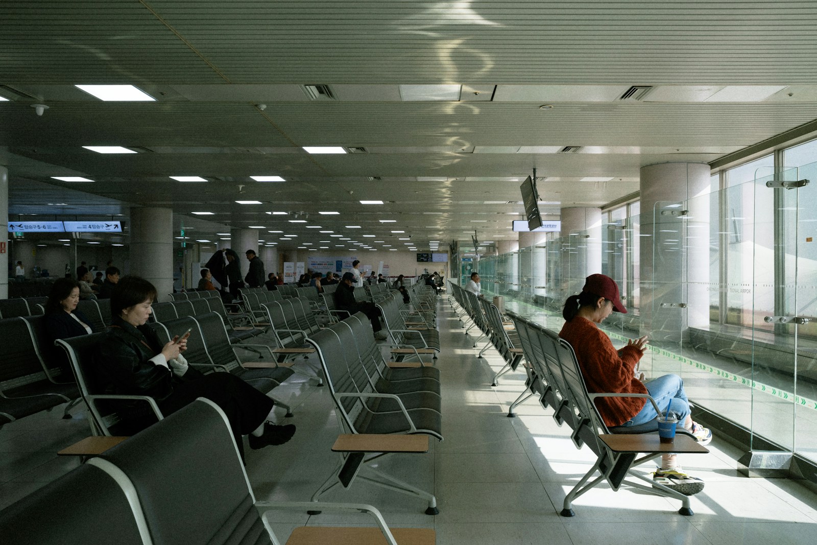 Travelers waiting in a modern airport terminal — the 1-mile Club pass gets you off those gate-area seats